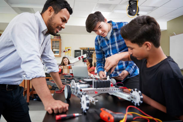 Teacher With Male Pupils Building Robotic Vehicle In Science Lesson Teacher With Male Pupils Building Robotic Vehicle In Science Lesson secondary school kids stock pictures, royalty-free photos & images